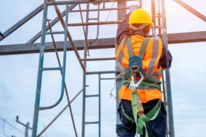 A team of diverse construction workers smiling, all wearing full PPE including hard hats, safety glasses, and high-visibility vests.