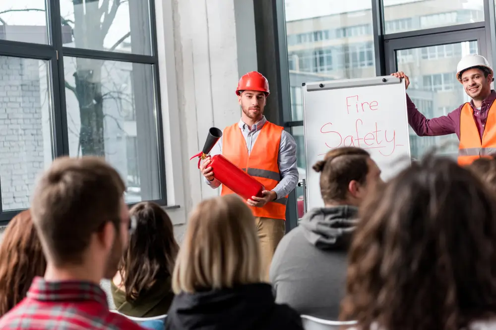 Workplace fire safety statistics showing workers in an industrial facility with fire prevention equipment